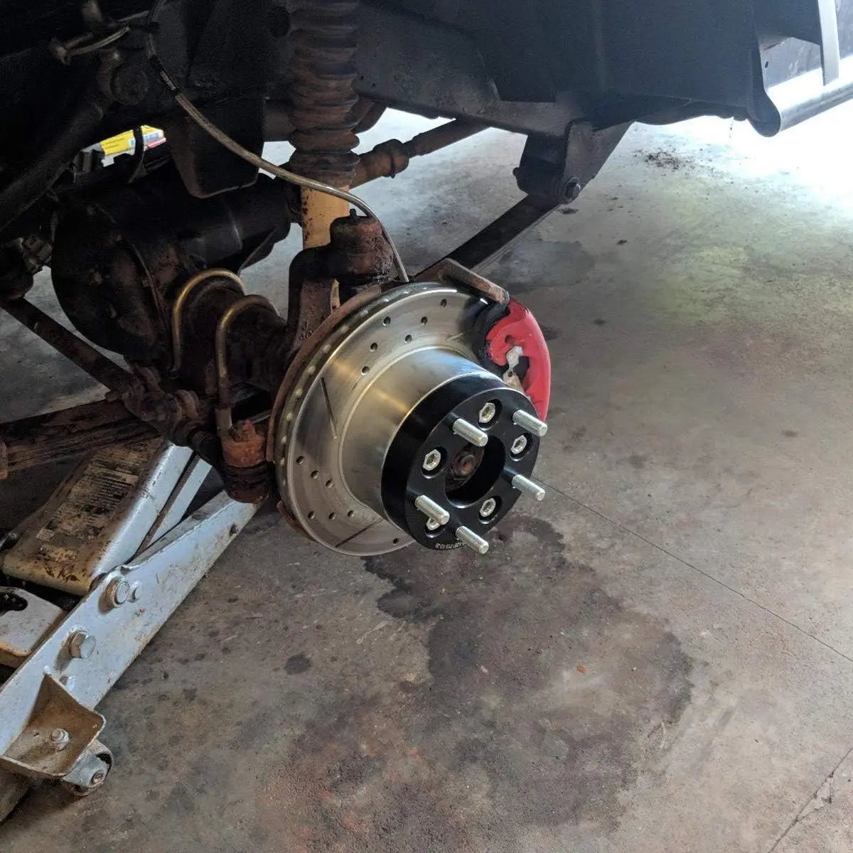 Dynofit Close-up of a car's brake system with a focus on the wheel hub and suspension components. 1.25" 5x4.5 to 5x5 Wheel Adapters for Jeep